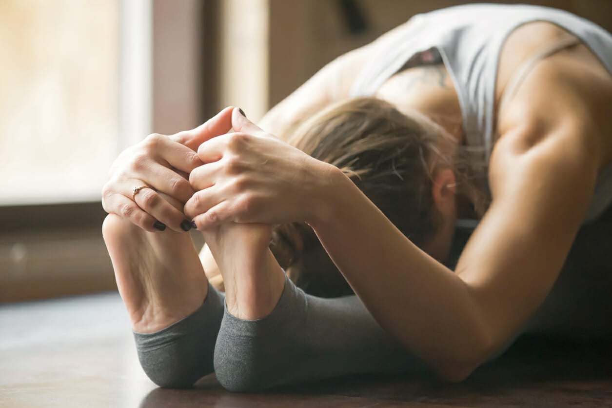 Young woman in paschimottanasana pose, home interior background,