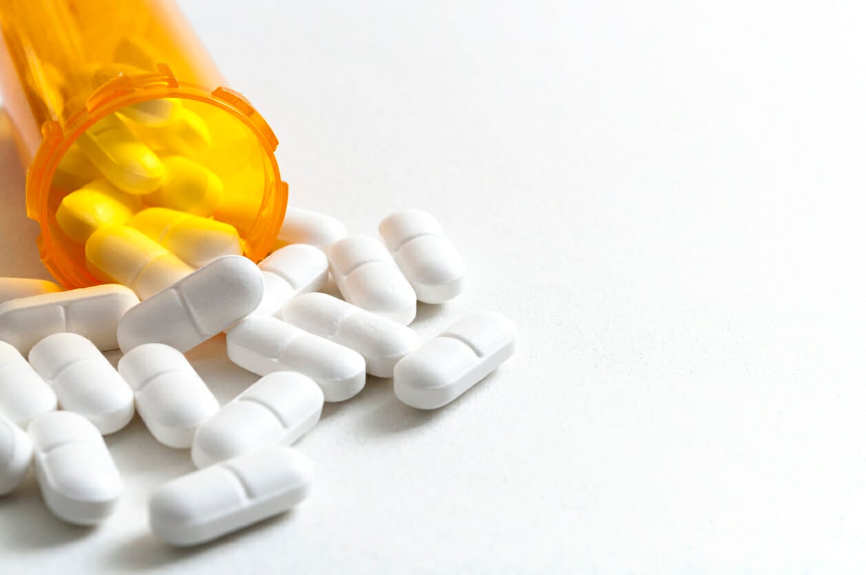 Hydrocodone capsules spilling out of a prescription bottle with copyspace