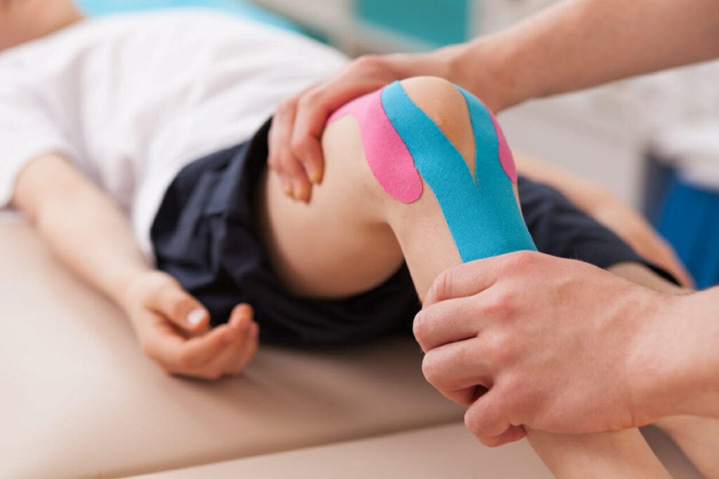 Sports physical therapist doing rehabilitation exercise for knee