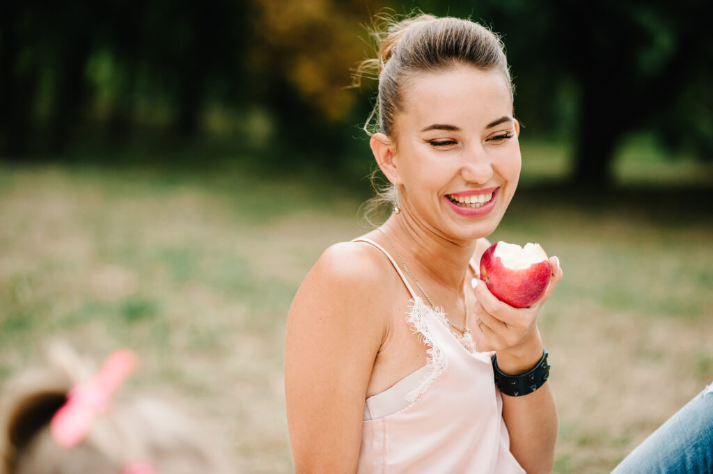 Girl eating an apple on a picnic in the summer