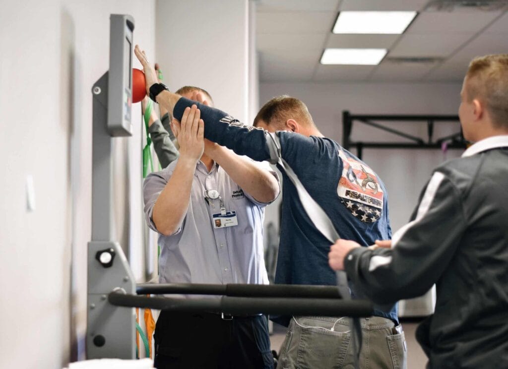 Physical therapists helping patient perform shoulder exercises