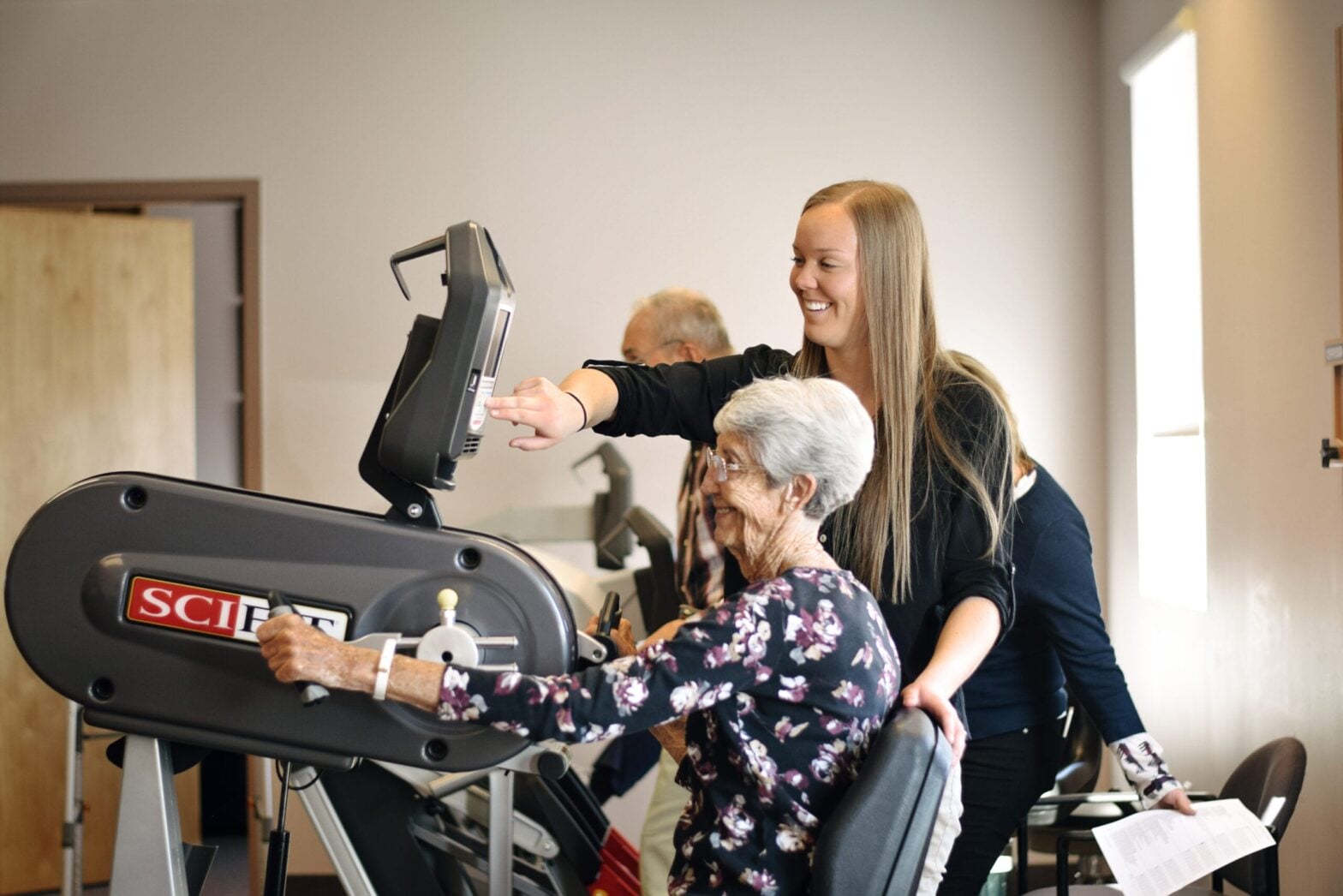 A Mountain Land clinician working with a patient on exercise equipment