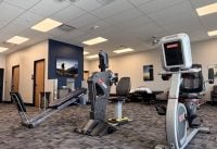 Cardio area in a gym with treadmills and a cross trainer, blue wall, and wall art in the background.