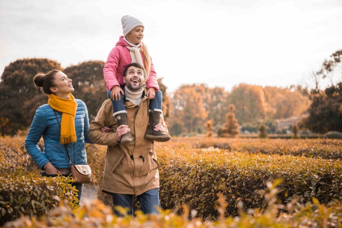 Happy family with one child walking in beautiful autumn park