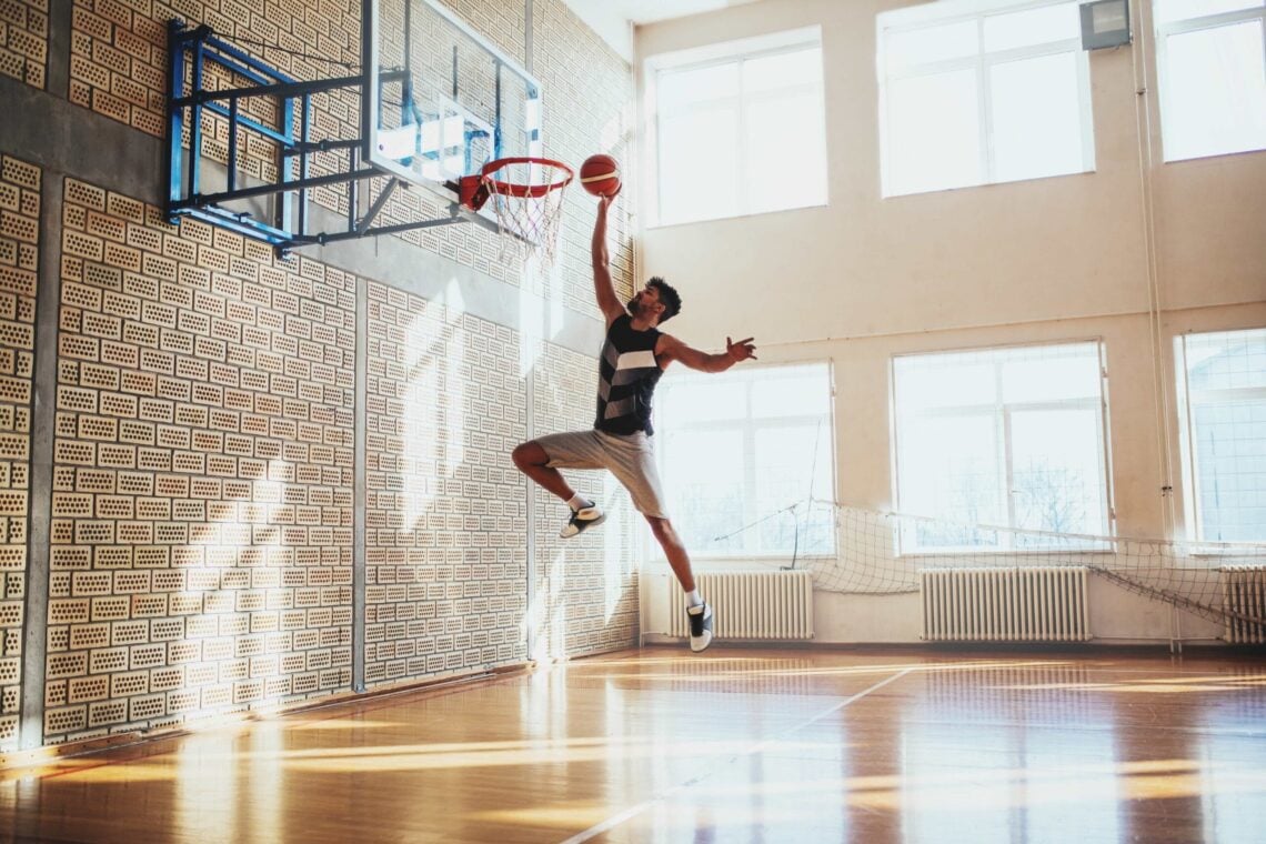 Shot of a young basketball player hammering a ball on the court.