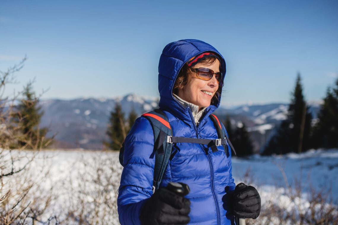 Portrait of happy senior woman standing in snow-covered winter nature.
