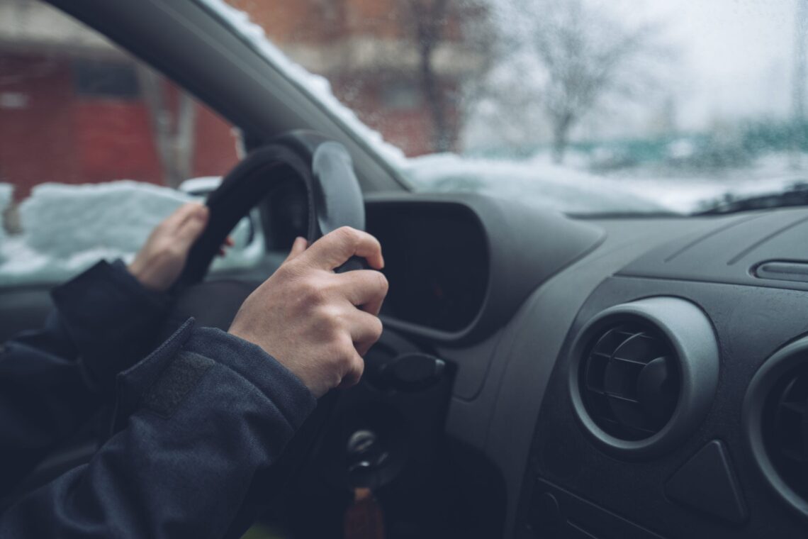 Waiting in car on winter day, female hands on steering wheel, selective focus